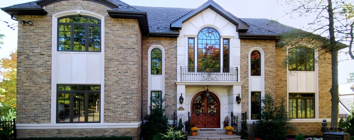 Tan brick house with arched windows and red double front door